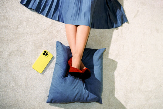 Top View of woman Resting Legs on Cushion with Smartphone Nearby