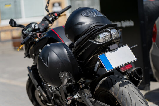 Naked sport bike tail section showing license plate and clear indicators with black motorcycle helmets on top, premium two wheeler vehicle design and individual mobility