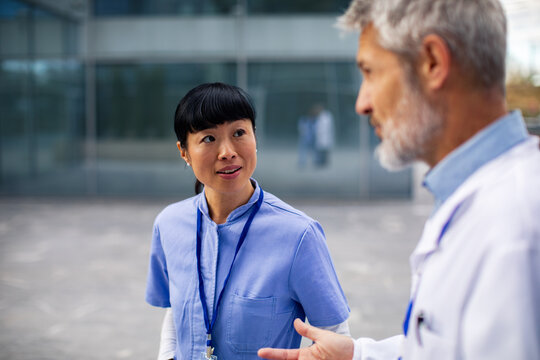 Nurse and doctor talking outside hospital building