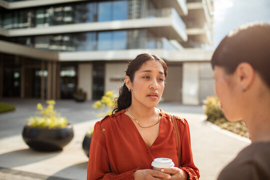Two coworkers having a serious conversation outside a modern office building