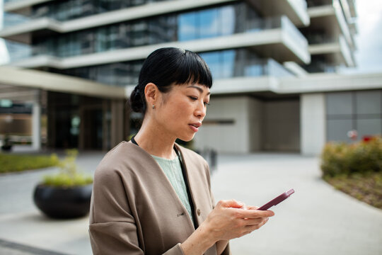Professional woman texting on smartphone outside office