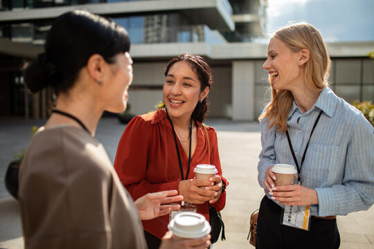 Businesswomen networking over coffee outside modern office