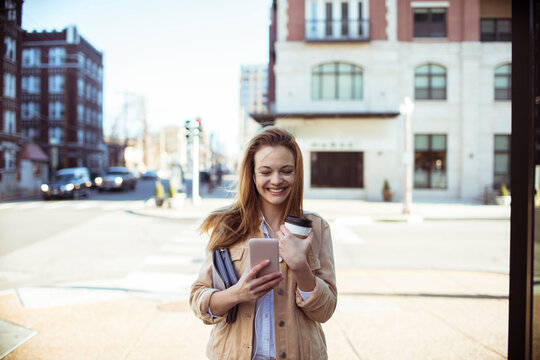 Smiling young woman using smartphone on city street