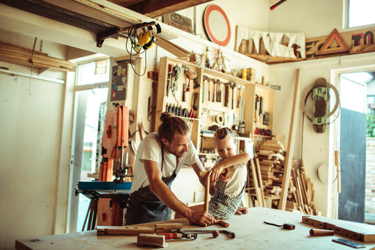 Father teaching daughter woodworking in sunny garage workshop