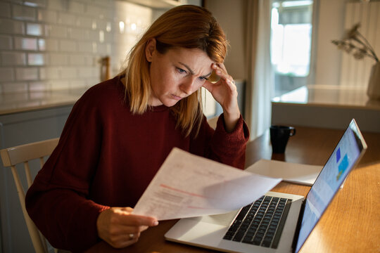 Stressed woman reviewing bills at home kitchen table