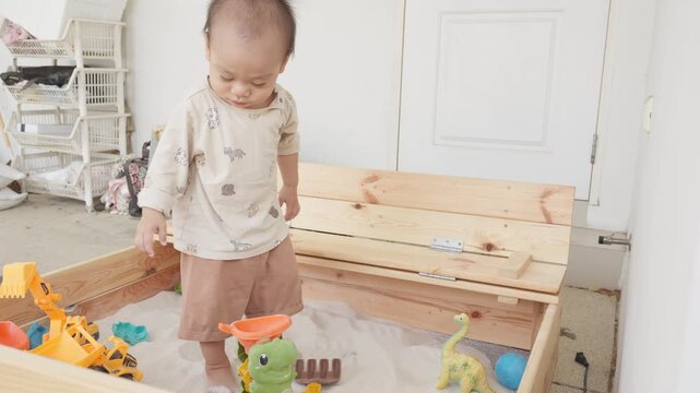 An indoor sandbox scene featuring a young child surrounded by colorful toys, promoting creativity and exploration. The child's engagement with the toys creates an atmosphere of joy and discovery.