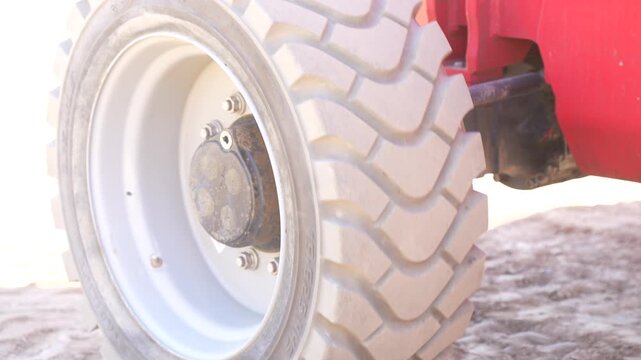 Deep tread profile of a red tractor loader wheel on dusty soil, mechanical transportation parts supply and agricultural machinery components market