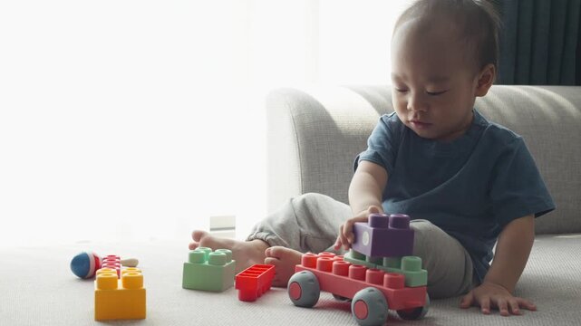 A young child is engaged in creative play, assembling colorful building blocks on a comfortable sofa. The vibrant colors and various shapes of the blocks encourage imagination and fine motor skills.