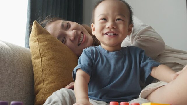 A heartwarming scene capturing the joyful interaction between a mother and her young child at home, surrounded by soft furnishings. The child's smile radiates happiness, showcasing the beauty of famil