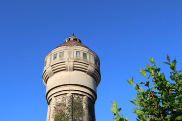 Obraz premium Historical Brick and Concrete Old Water Tower with Climbing Ivy Against Clear Blue Sky in Romania, Timisoara