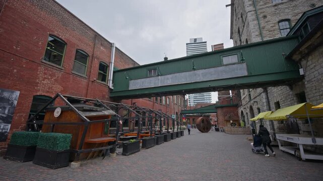 People walking through historic Distillery District in Toronto with outdoor patios, industrial architecture, brick buildings, cobblestone streets