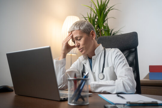 Headache, tired doctor and woman in medical office with burnout challenge, clinic problem and stress risk. Frustrated female healthcare worker with fatigue, migraine pain and anxiety of mistake