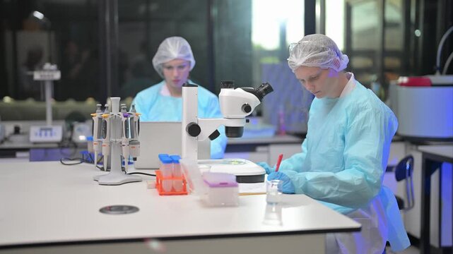 Scientists work in lab using microscope for research in a biomedical facility