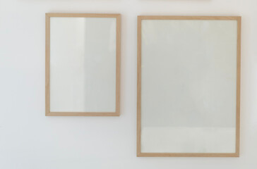 Fototapeta premium Two blank wooden poster frames hanging on white wall mockup template
