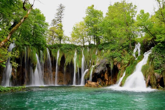 Waterfalls in Plitvice Lakes with blue, turquise water amd trees ath background