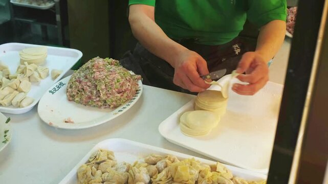 Worker making Chinese dumplings jiaozi with meat filling in restaurant. Authentic culinary craft and food preparation concept for Chinese restaurant cuisine.
