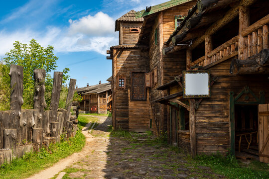 The impressive wooden walls of a reconstructed Old Slavic fortress, made of round, hewn logs. Old barracks and boyar chambers. A bright, sunny day.