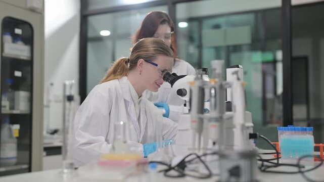 Scientists in lab coats working with microscopes and test tubes in a modern laboratory