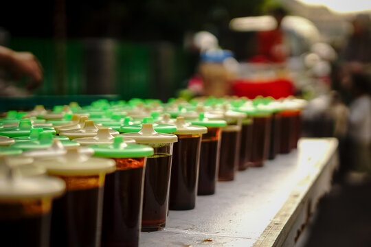 Lined up glasses of sweet tea with green lids on a table at a local street food vendor.