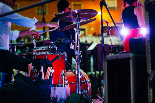 Drummer playing drums during a live music concert with musicians on stage