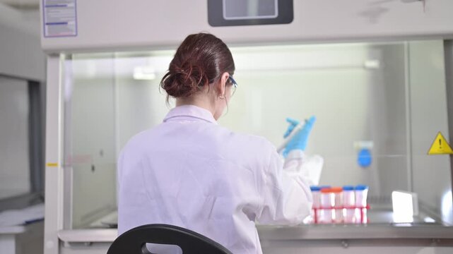 Scientist working in a sterile laboratory fume hood with test tubes