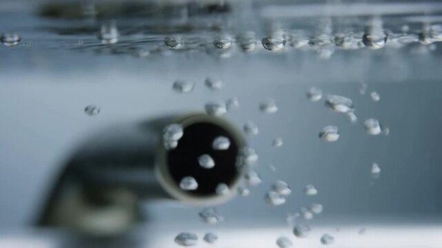 Bubbles rising from underwater pipe in rippled water environment