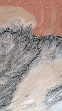 Vertical flying over dramatic desert and mountain landscape with natural geological patterns satellite view from space