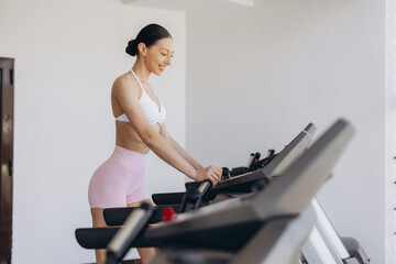 Fototapeta premium Fit woman walking on a treadmill, actively engaging in a cardio workout for health and strong physique