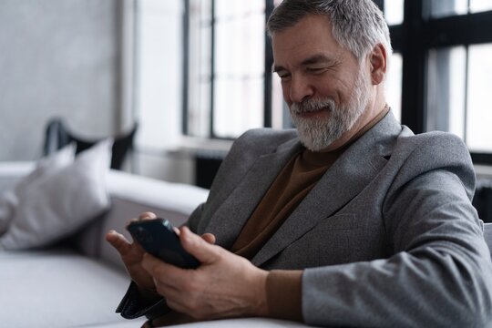 Mature smiling man using smartphone