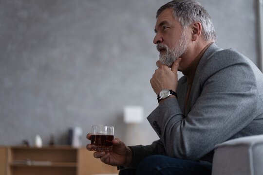 Confident mature businessman chilling relaxing drinking enjoying whiskey after work.