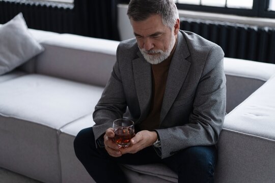 Confident mature businessman chilling relaxing drinking enjoying whiskey after work.