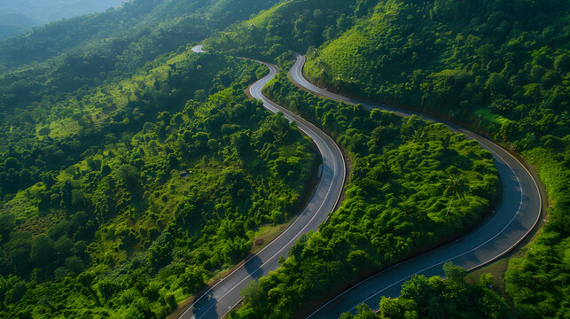 Aerial view of a winding road through a lush green tropical forest in the mountains