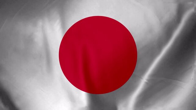 Close up of the Japanese flag waving with a red circle on a white background showing fabric texture and folds
