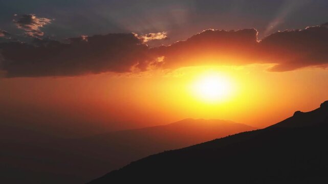 Timelapse cinematic golden sunset mountains sun rays piercing clouds dramatic sky silhouette nature landscape spiritual hope inspiration light rays wilderness horizon outdoor vista. Gods suns eye
