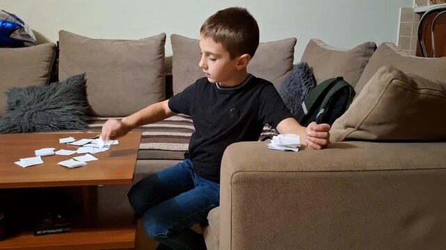 Child sorting cards on a couch in a living room while focused and engaged in activity
