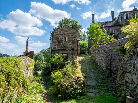 Beautiful old stone houses in Hollins a hamlet on the outskirts of Hebden Bridge on a cobbled land surrounded by summer trees and flowers