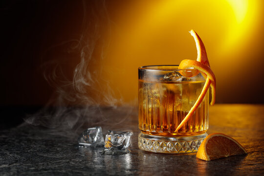  Whiskey with ice in a fogged up glass on a black stone table.