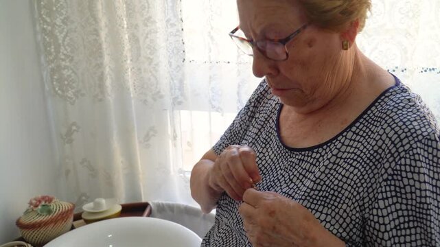 An older woman puts a gold brooch on her shirt