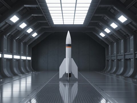 White rocket model on launchpad in large industrial hangar with gray walls and floor
