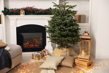 Obraz premium Beautiful Christmas tree and other festive decor near fireplace in living room