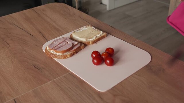 The housewife takes out cherry tomatoes in order to add them to the sandwich filling.