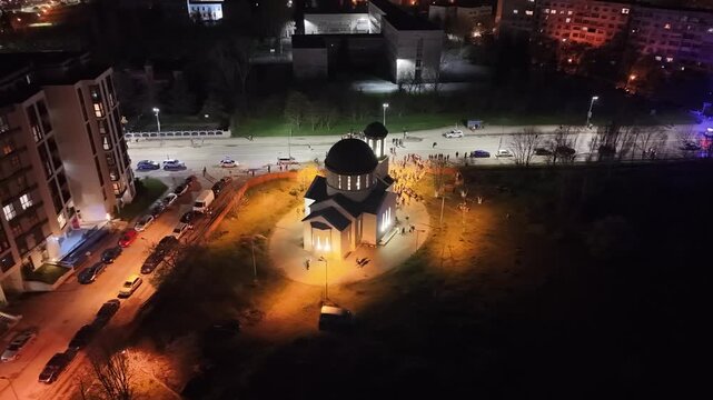 Aerial night view of an illuminated orthodox church during Easter midnight mass celebration. Drone shot of people gathered outside the temple for the Resurrection of Christ in Bulgaria.