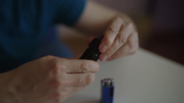 Close-up view of male hands refilling modern vape pod system with nicotine salt e liquid from bottle, illustrating process of maintaining electronic cigarette for vaping. Shooting in slow motion