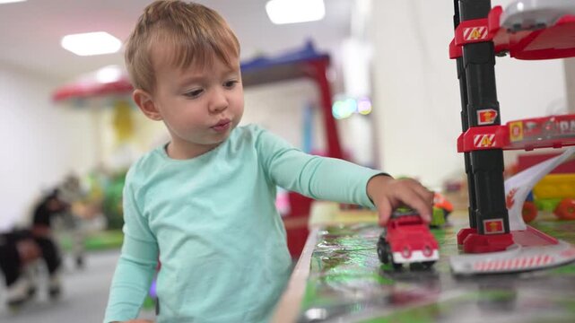 Young child playing with toy train. Boy, plays, railroad, toys carriages, train, son. A train with carriages and a boy playing with it. The photo is of a child playing with lifestyle a toy train.