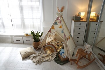 Cute wigwam with fairy lights and toys in stylish child's room, above view © New Africa