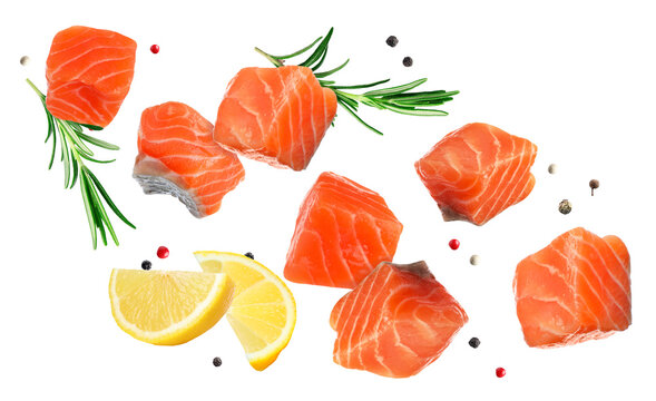 Salmon pieces, lemon, rosemary and peppercorns flying in air on transparent background