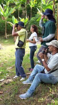 A group of people are observing nature using binoculars in an outdoor setting.