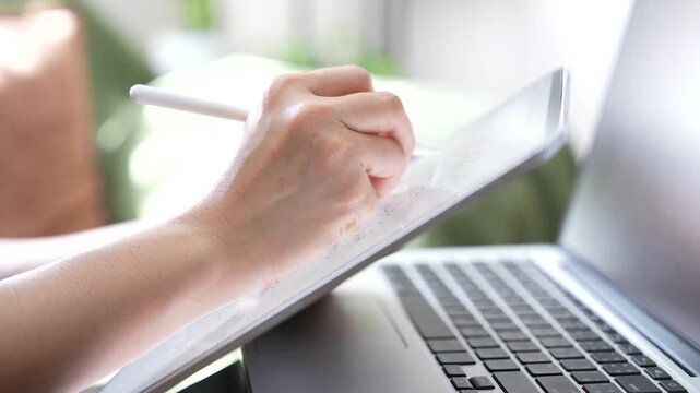 Close up of hand managing customer orders on tablet with laptop background. Order confirmation, email communication, e commerce workflow, customer service and online business management.