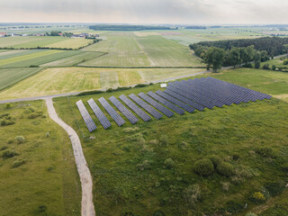 Aerial high angle view of a solar farm with rows of photovoltaic panels in a rural field landscape surrounded by trees in Poland © Jakub