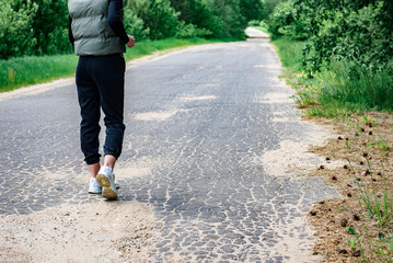Fototapeta premium Rear view of a woman's legs in sportswear before running on early spring forest background.